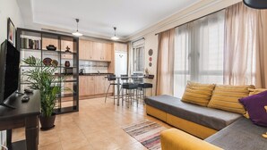 A modern living room with a sofa, a TV, and a dining area with chairs and a table. - Home2Book Bright Retreat with Pool, Sardina Beach (Gáldar)