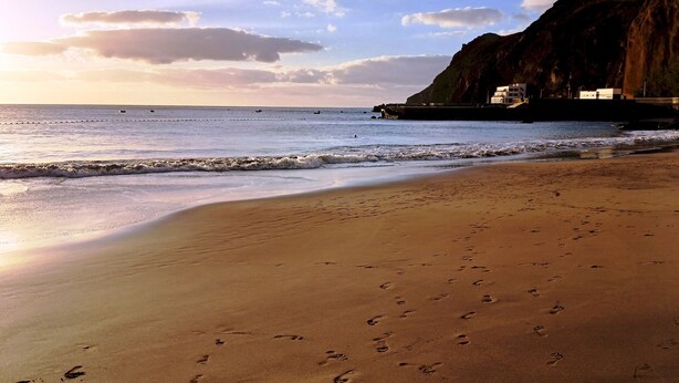 A beach with footprints in the sand, a rocky cliff, and a calm sea. - Home2Book Bright Retreat with Pool, Sardina Beach (Gáldar)