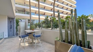 A balcony with a table and chairs, surrounded by cacti and potted plants.