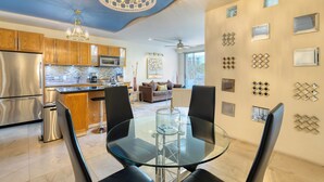 A modern kitchen with stainless steel appliances, a glass dining table, and a ceiling fan.