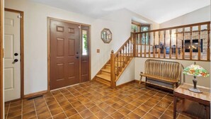 A hallway with a wooden staircase, a bench, and a door. - Beautiful Four-Level Split Home @ Calm Cul-de-sac! (Roseville)