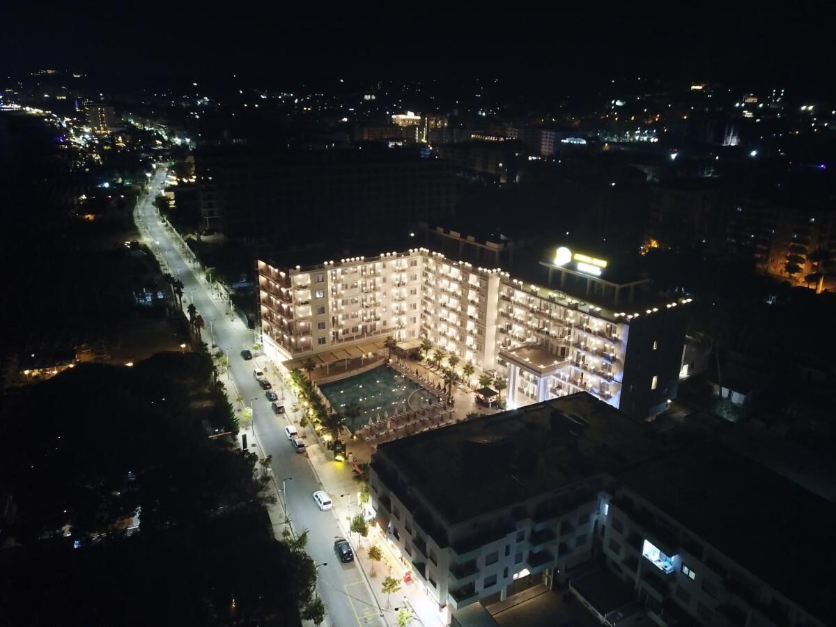 A multi-story hotel with a central courtyard, surrounded by a well-lit street and other buildings.