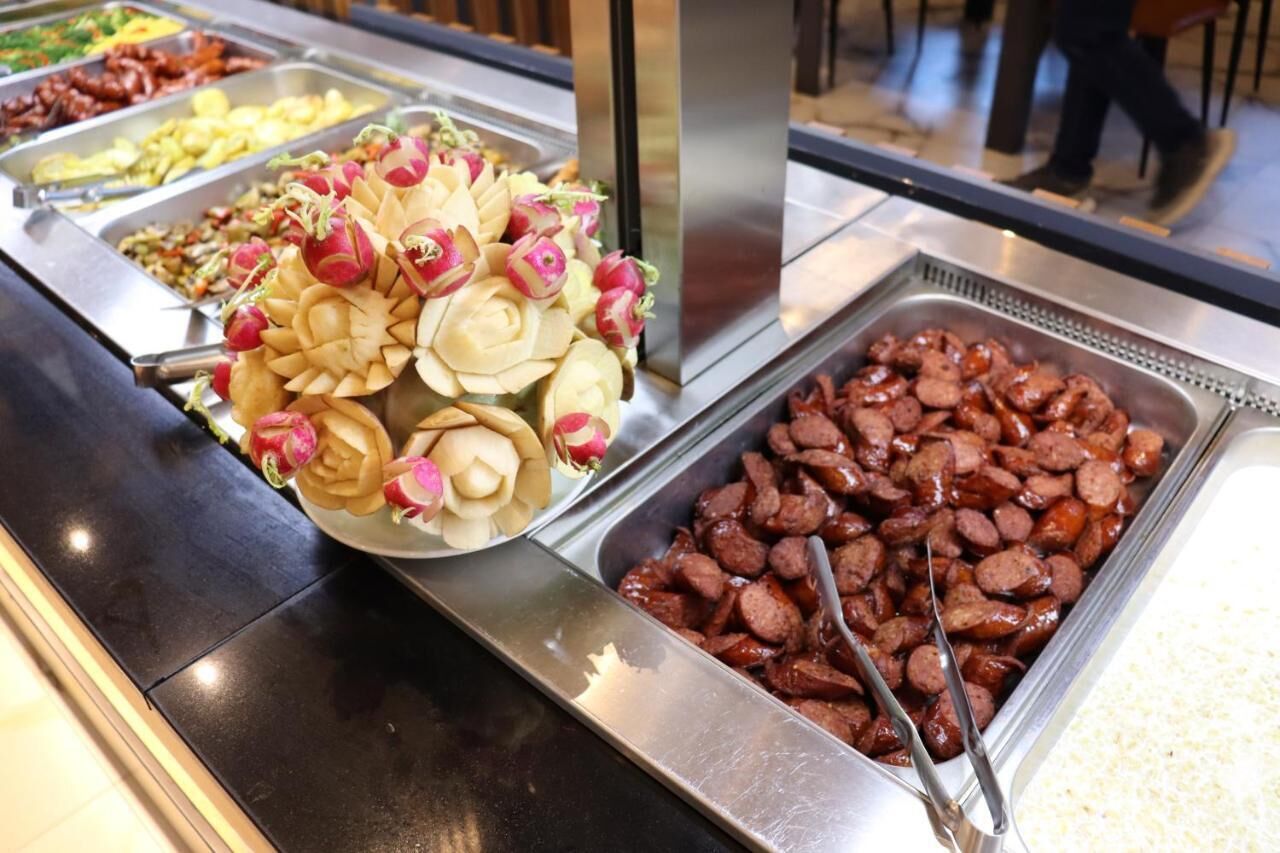 En buffet med forskellige retter, herunder skiveskårne radiser og pølser.
