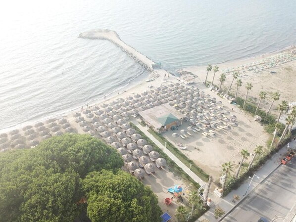 Aan een privéstrand, parasols, strandlakens, beachvolleybal