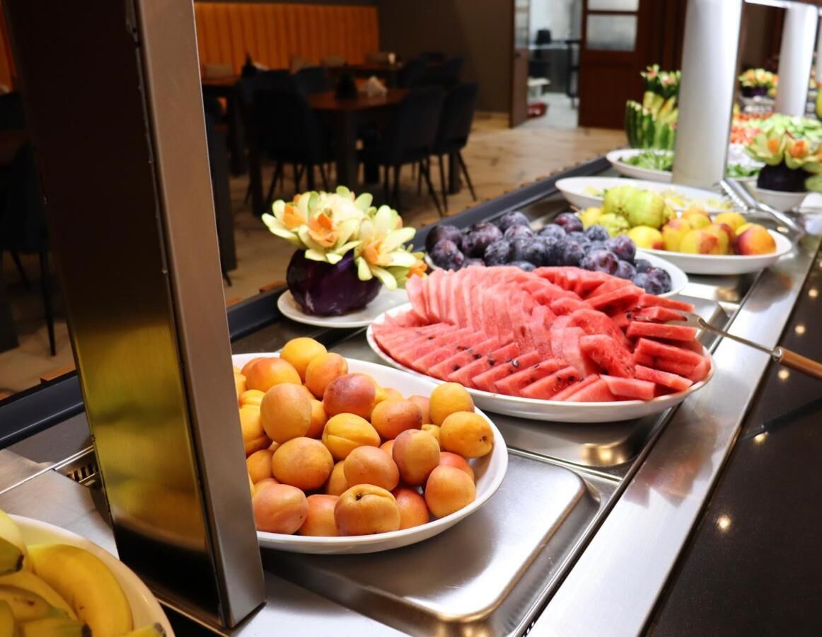 Un buffet proposant une variété de fruits, notamment des pastèques, des pêches et des bananes.