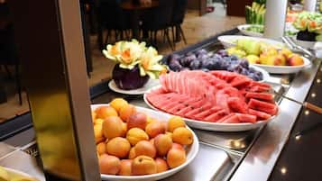 Un buffet proposant une variété de fruits, notamment des pastèques, des pêches et des bananes.