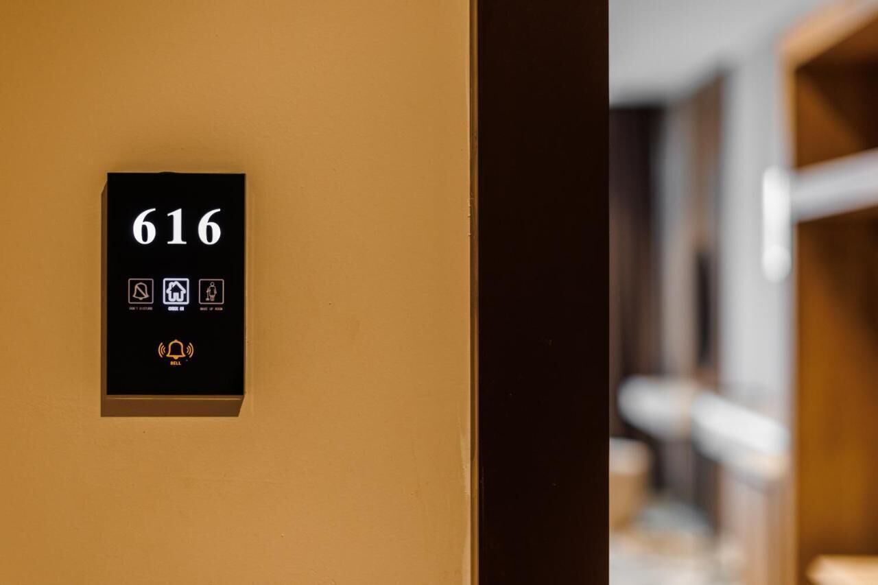 Hotelkamer 616 met een zwart paneel waarop iconen voor kamervoorzieningen en een bedieningsknop staan.