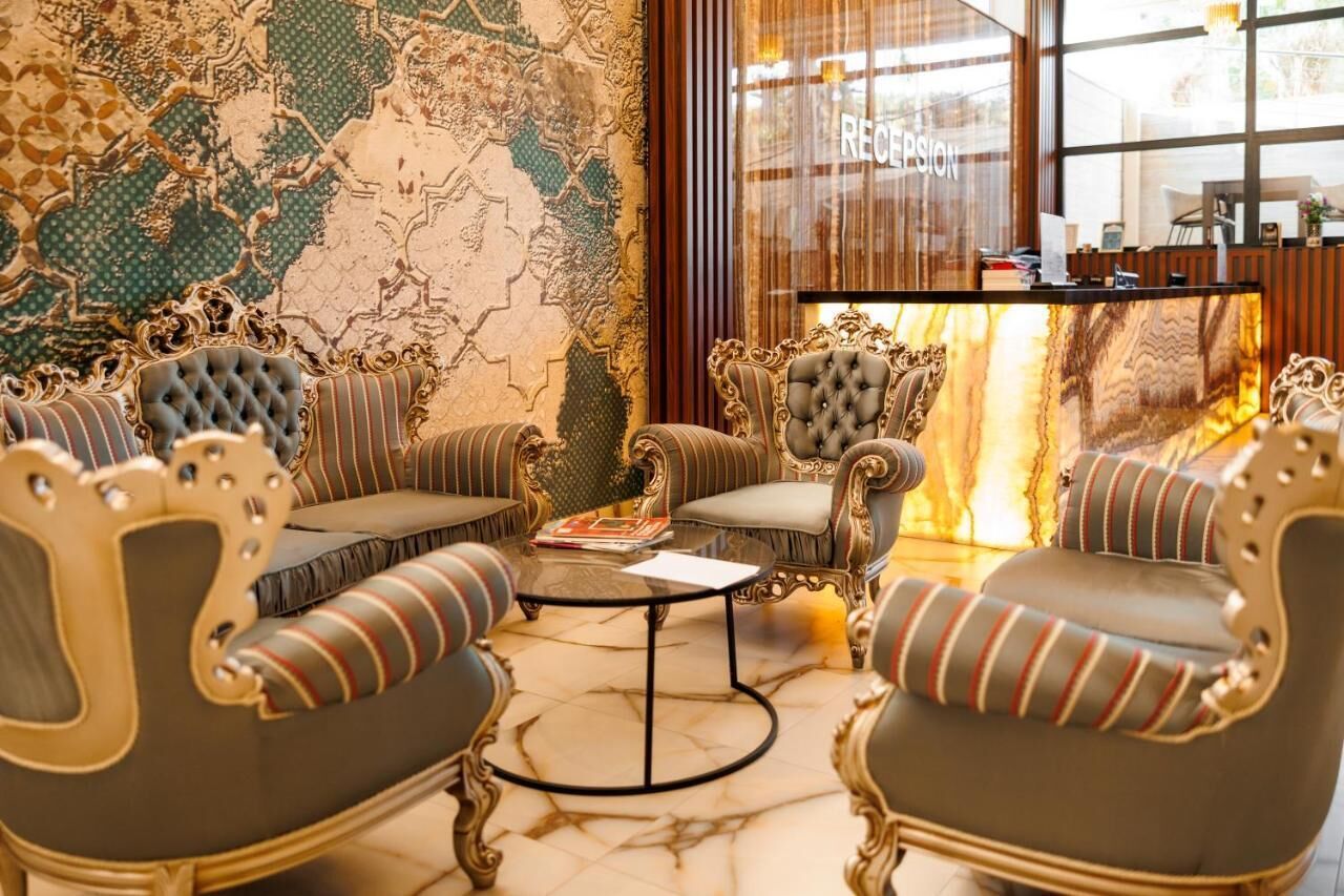 A luxurious lobby with ornate chairs, a marble floor, and a reception desk.
