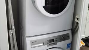 Une machine à laver compacte, blanche, à deux portes, dotée d’un panneau de commande et d’un compartiment pour la lessive situé sur le dessus.