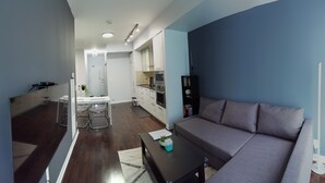 Un espace de vie compact comprenant un canapé, une table à manger et une kitchenette.