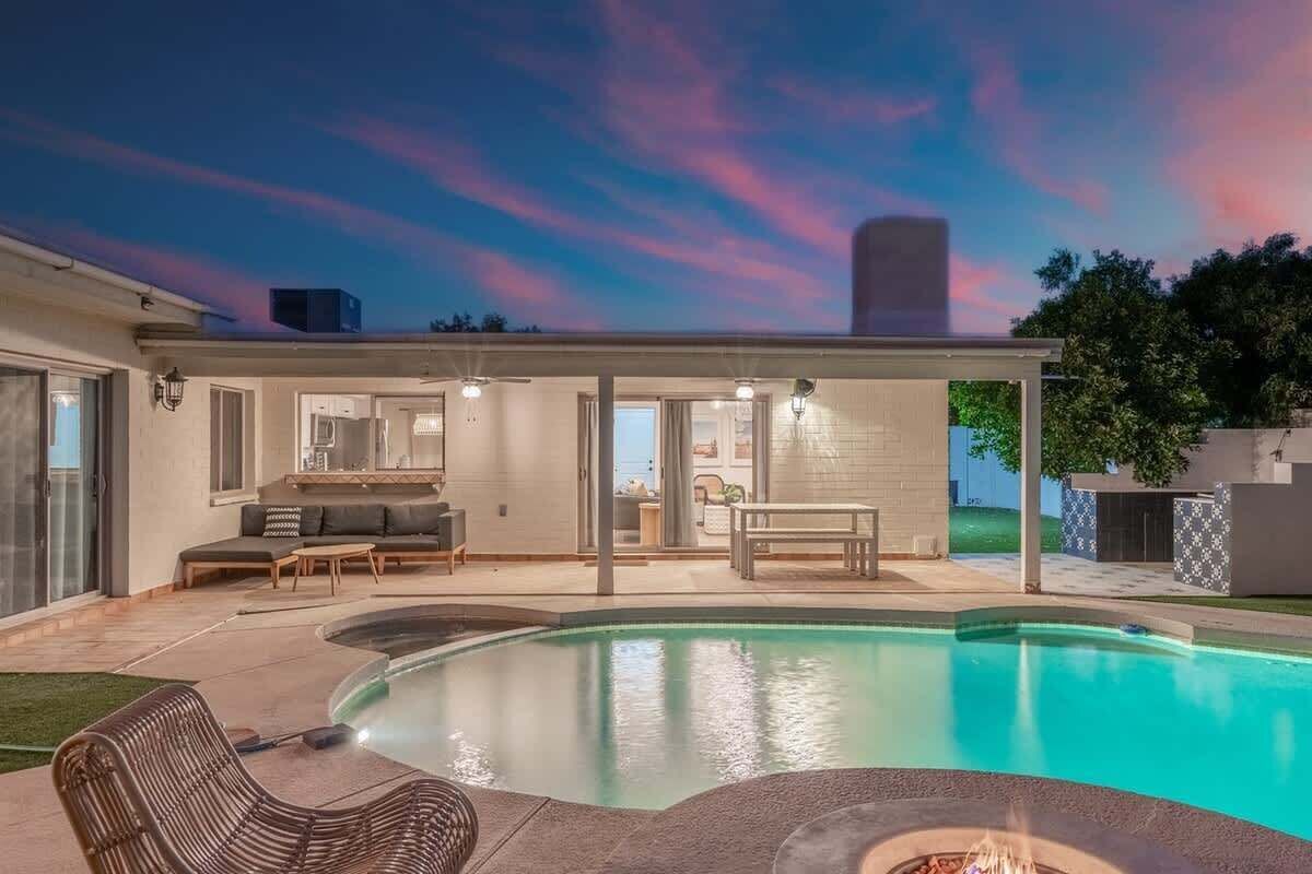 A modern house with a swimming pool, outdoor seating, and a fire pit.
