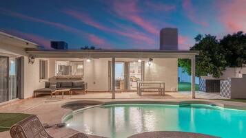 A modern house with a swimming pool, outdoor seating, and a fire pit.