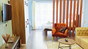 A modern hotel room with a wooden wardrobe, a flat-screen TV, a sofa, a coffee table, and a bed with a white headboard. - Comfy Apartment-Pool & Gym in Kilimani- Nairobi Near National Park (Nairobi)