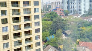 A high-rise building with multiple balconies and a view of surrounding residential buildings and greenery. - Comfy Apartment-Pool & Gym in Kilimani- Nairobi Near National Park (Nairobi)