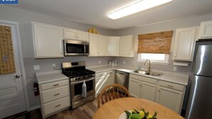 A compact kitchen with white cabinets, a stainless steel stove, a microwave, and a refrigerator.