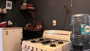 A kitchen with a white gas stove, a refrigerator, and a water dispenser. - Private room for 5 people. A/C, TV, Wi-Fi, minibar, kitchen and living. Downtown | Isla Mujeres  #2 (Isla Mujeres)