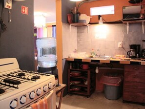 A kitchen with a stove, sink, and various utensils.