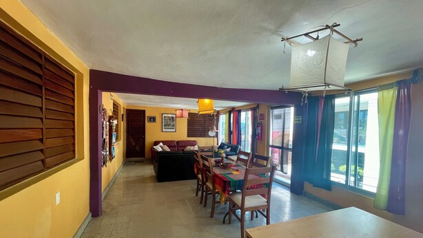 A dining area with a wooden table and chairs, a sofa, and a hanging light fixture. - Private room for 5 people. A/C, TV, Wi-Fi, minibar, kitchen and living. Downtown | Isla Mujeres  #2 (Isla Mujeres)