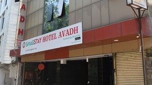 Un hôtel avec une enseigne indiquant « HÔTEL AVADH » et une grande publicité pour « SWAGSTAY HÔTEL AVADH ».
