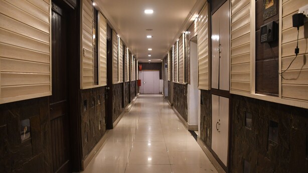 Un couloir d’hôtel avec des casiers, un sol carrelé et une porte au fond.