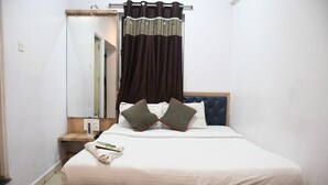 Une chambre à coucher avec un lit, une table de chevet, un miroir et un rideau.