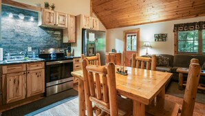 Una cocina rústica con armarios de madera, un respaldo de piedra y un comedor con sillas y una mesa de madera.
