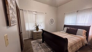 A bedroom with a bed, a nightstand, a vase with flowers, and a wall clock.