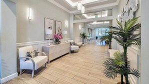 A spacious lobby with a reception desk, seating area, and potted plants.