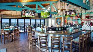 A bar area with a high ceiling, wooden beams, and a view of the city.
