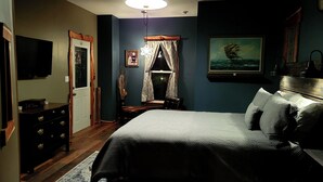 Un dormitorio con cama, cómoda, escritorio y un cuadro en la pared.