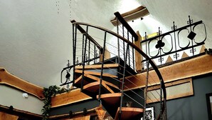 Un interior rústico con una escalera en espiral, barriles de madera y una guitarra.