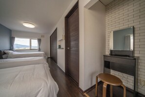 Ein Hotelzimmer mit zwei Betten, einem hölzernen Hocker, einem Fernseher und einer Wand mit Backsteinmuster.