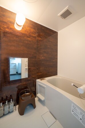 Ein modernes Badezimmer mit großem Spiegel, einer Badewanne und einer Toilette.