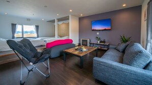 A modern living room with a sofa, a chair, a coffee table, and a TV mounted on the wall. - THE FURANO HIBIKI (Furano)
