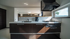 A modern kitchen with a central island, built-in appliances, and a window providing natural light. - THE FURANO HIBIKI (Furano)