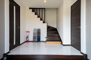 Un interior moderno con una escalera, un extintor y un par de zapatos en el suelo.