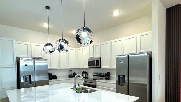 Una cocina moderna con armarios blancos, electrodomésticos de acero inoxidable y una isla central.