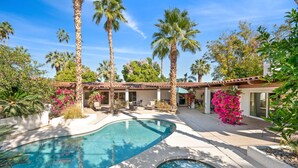 A pool area with palm trees, a patio, and a building with a tiled roof. - Grapevine Getaway -Large Home With Views, Pool+Spa (Palm Desert)