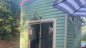Una casa móvil verde con puerta corredera, un pequeño porche y un espacio de patio.