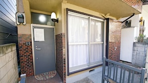A residential building with a gray door, a window with curtains, and a brick exterior. - -Takaya house- Minamirokugou close Haneda AP (Ota City)