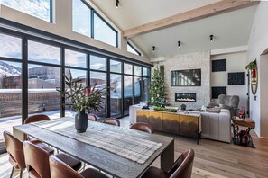 Amplia sala de estar con un ventanal, chimenea y mesa de comedor con sillas.