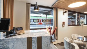 Un comptoir d’accueil d’hôtel au design moderne, avec un téléphone et une vue sur la rue.