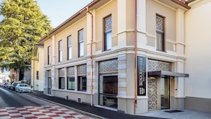 Un hôtel à la façade classique, avec une entrée imposante agrémentée d’un portail décoratif, de nombreuses fenêtres et une vue dégagée sur la rue.