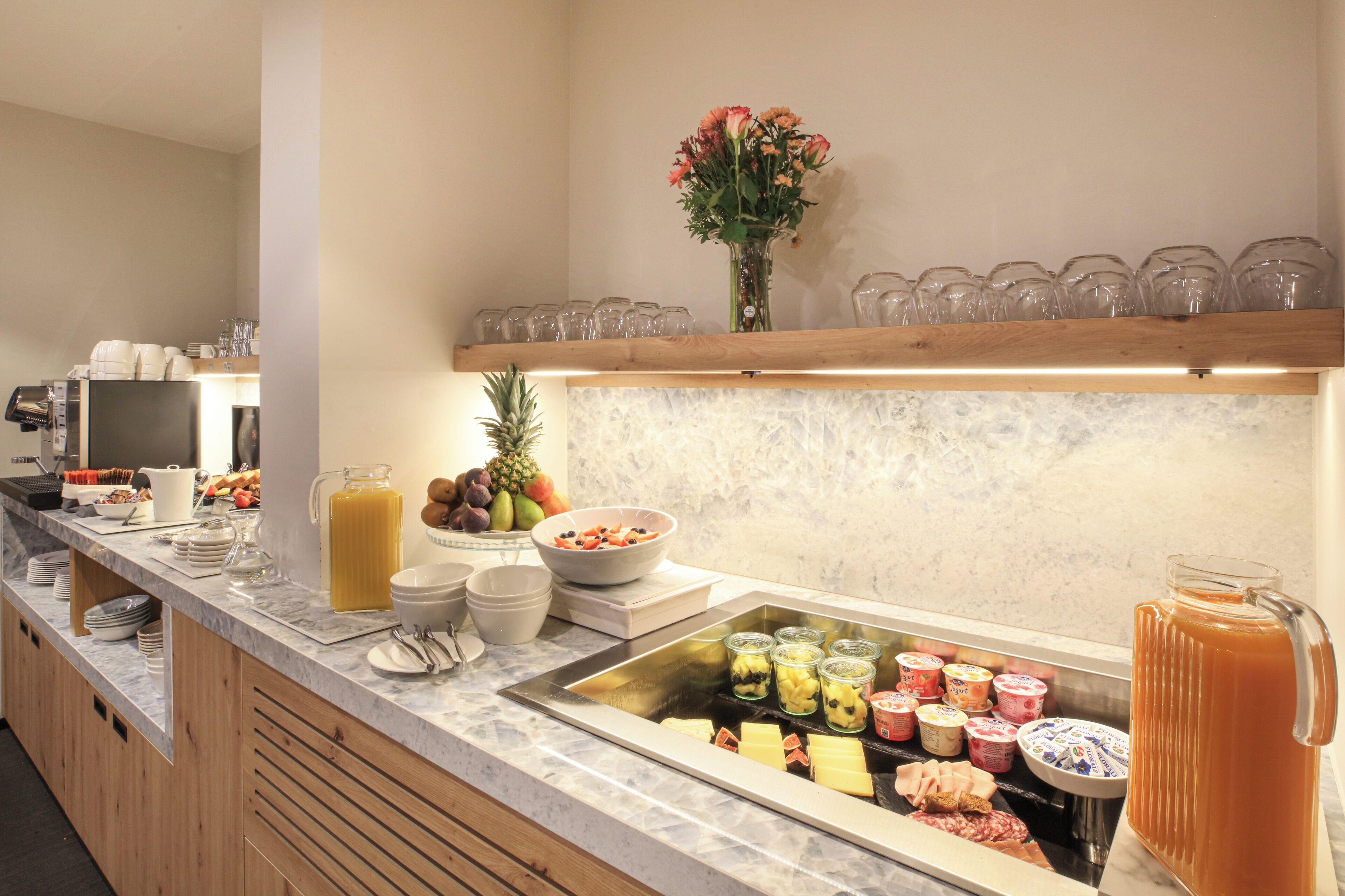 Un buffet proposant une variété de plats, un saladier rempli de fruits et un distributeur de jus.