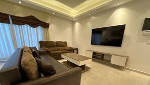Una sala de estar moderna con un televisor de pantalla plana grande, un sofá y una mesa de centro.