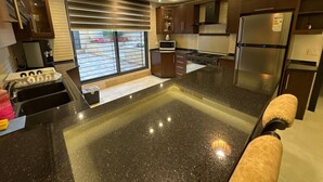 Una cocina moderna con una isla grande, electrodomésticos de acero inoxidable y vistas al exterior.