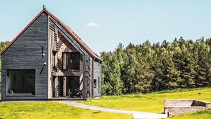 Une maison rustique en bois, dotée d’un toit en pente, d’une grande fenêtre et d’un petit porche.