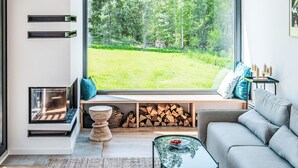 Un salon moderne doté d’une grande fenêtre donnant sur un paysage verdoyant.