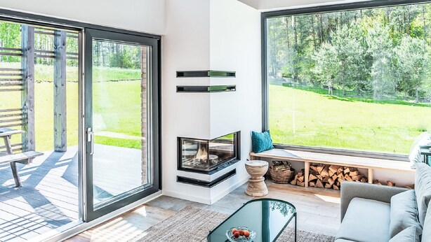 Un intérieur moderne avec une cheminée, de grandes fenêtres, une terrasse et un coin salon confortable.
