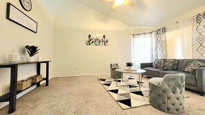 Un salon avec un canapé gris, une table basse ronde et un tapis à motifs.